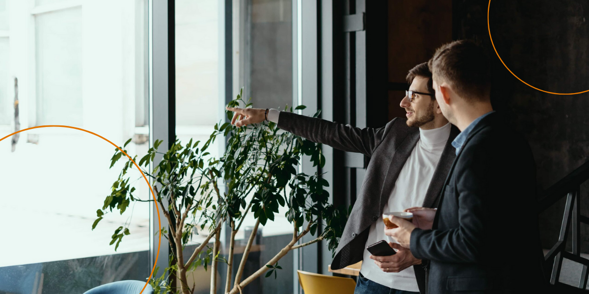 Two businessmen discuss while one points outside