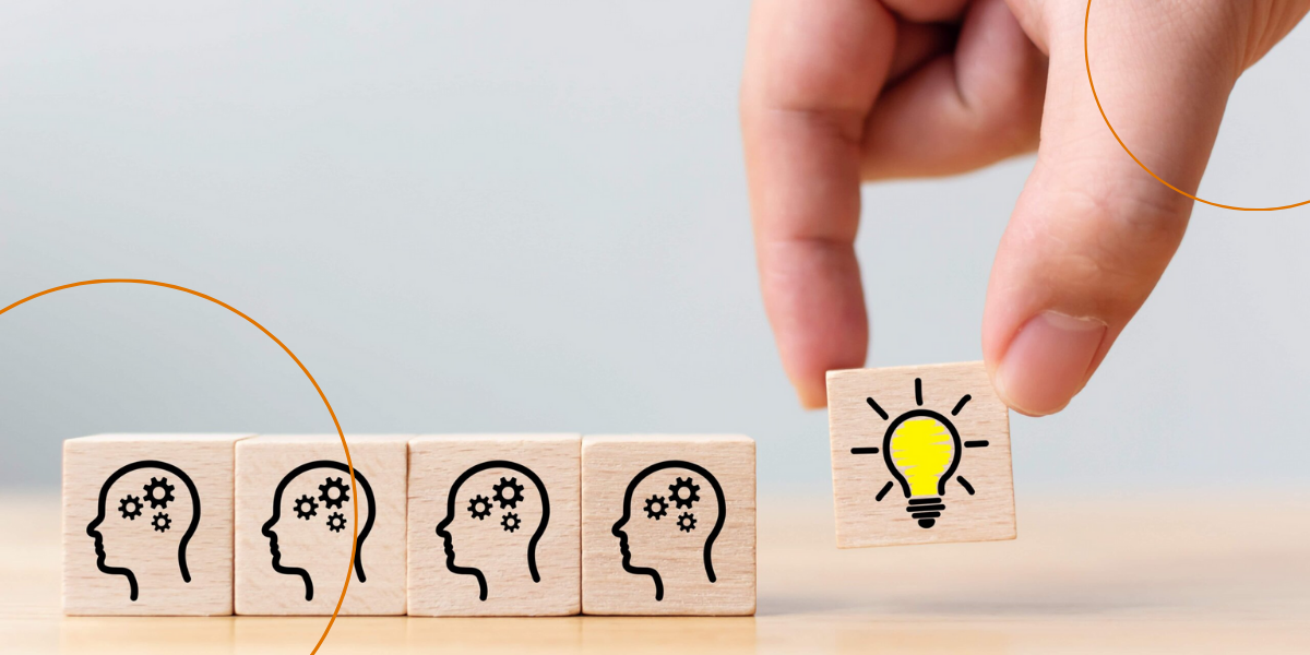 A hand sets down a wooden block with a lightbulb on it next to other wooden blocks with brains on them
