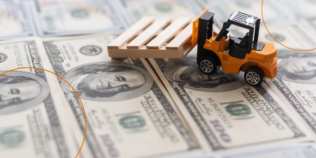 A toy excavator moves a pallet over one hundred dollar bills