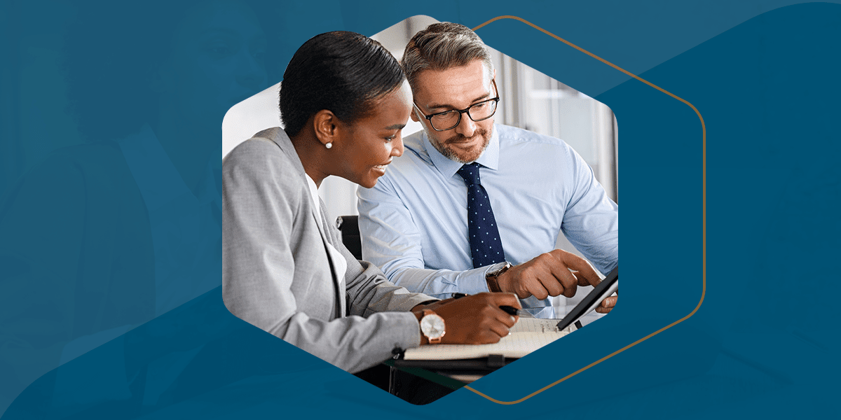 A male and female in business clothes look at a tablet