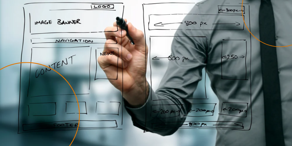 A man draws designs on a clear whiteboard